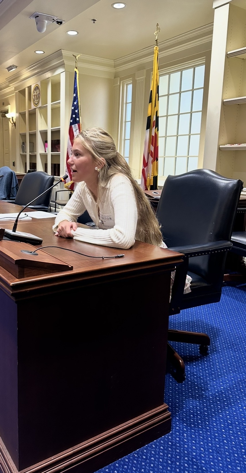 Cally speaking into a microphone at a meeting table in Annapolis
